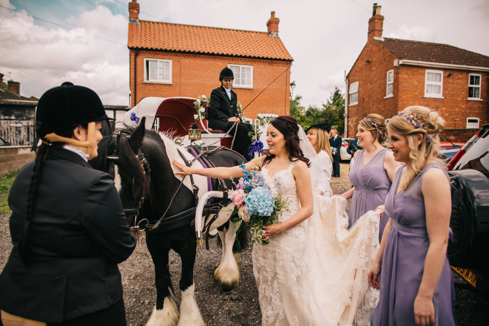 bride standing next to horse carriage and being photographed by Wedding Photographer Lincolnshire