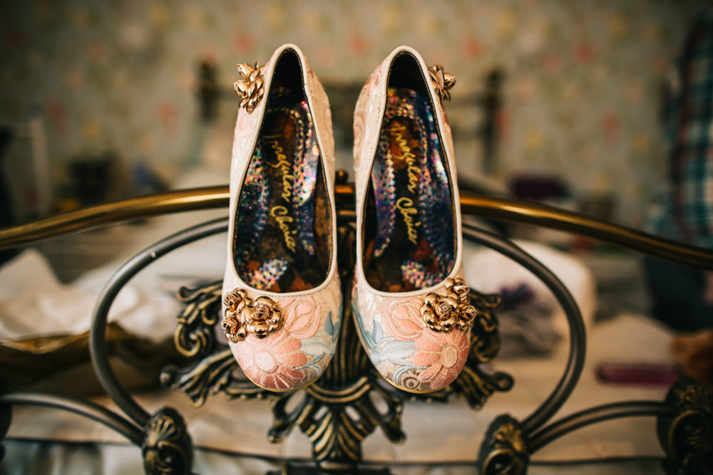 pink wedding shoes with golden roses hanging on the bed 