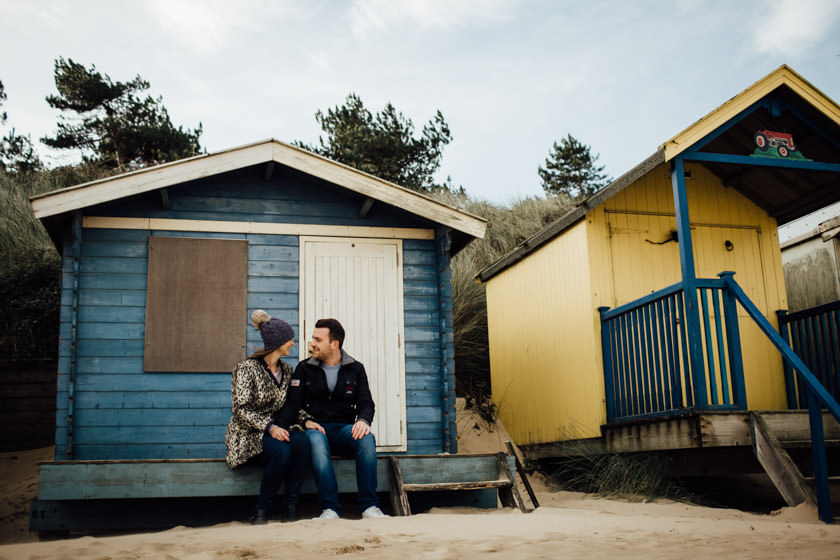 couple sitting on a beach hut steps on the beach in Norfolk 
