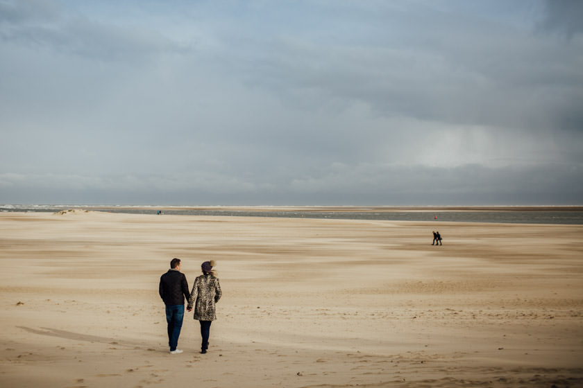 couple holding hands on the beach and walking towards the sea