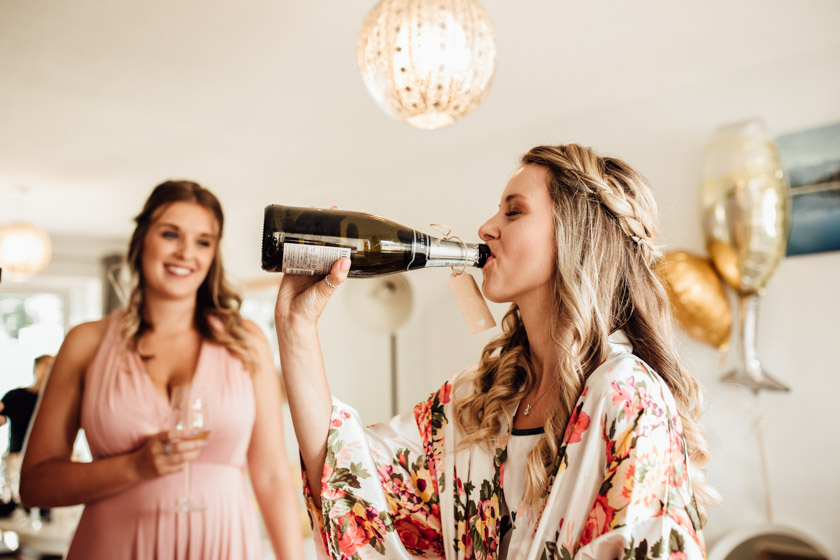 bride drinking champagne straight from the bottle photographed by Park Farm Wedding Photographer