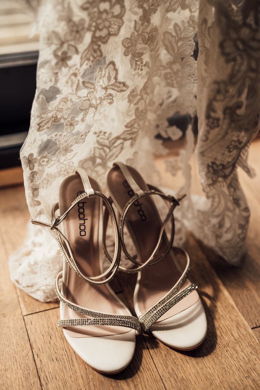 wedding shoes next to lace wedding dress